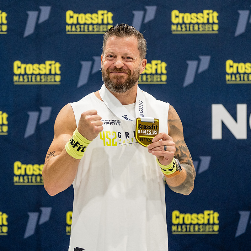 Jason Grubb holding Crossfit Games Medal for 2024 smiling with Crossfit Masters background
