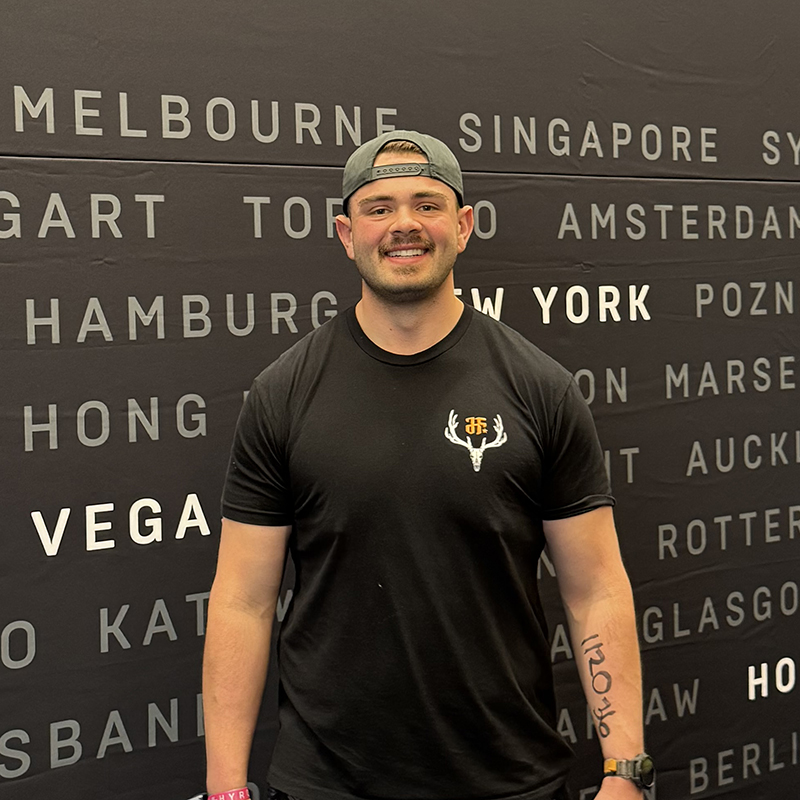 Nate Illingsworth smiling at an athletic event with a backdrop of global city names
